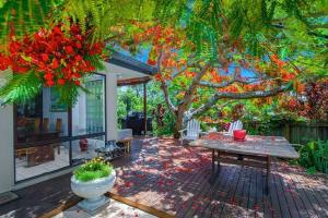 eine Terrasse mit einem Tisch und einem Baum in der Unterkunft Beautiful 2Bdr House with Pool in Byron Bay