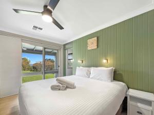 a bedroom with a white bed with a green wall at Martha's Homestead in Lovedale