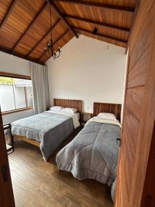 a bedroom with two beds and a large window at chalé cantin casa temporada 900 m praça tiradentes in Tiradentes