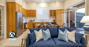 Una sala de estar con un sofá azul y una cocina. en Seaspray Cottage Holiday Accommodation Victor Harbor, en Victor Harbor