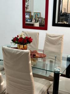una mesa de cristal con sillas blancas y un jarrón con flores en Una Joya brillante, en San Antonio