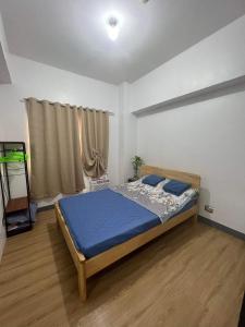 a bedroom with a bed with blue sheets and a window at One Bedroom Condo with fast wifi at Eastwood Lafayette tower Quezon city in Manila