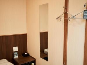 um pequeno quarto com um espelho e uma cama em Grand Cabin Hotel Naha Oroku for Men / Vacation STAY 62323 em Naha