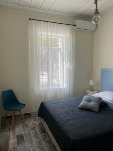 een slaapkamer met een bed, een raam en een stoel bij 1922 Historic House in Kavala