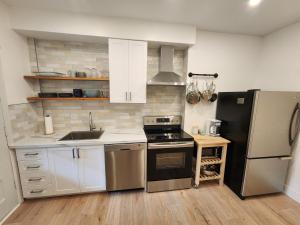 uma cozinha com armários brancos e um frigorífico preto em Elegant two bedroom with office in Montreal em Montreal