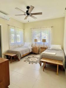 a bedroom with two beds and a ceiling fan at FlowerPot by the Sea in Lucea