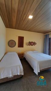 two beds are in a room with a ceiling at Eloa Flats in Luis Correia