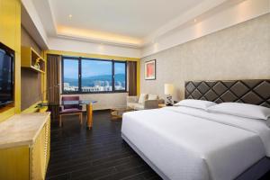 a hotel room with a large bed and a desk at Four Points by Sheraton Hainan, Sanya in Sanya