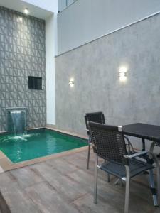 a pool in a room with a table and chairs at Residência Cidade Verde 3 in Maringá