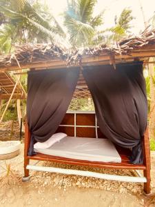 a bed in a hut with a mosquito net at Destiny Rainbow Beach Resort in Siquijor
