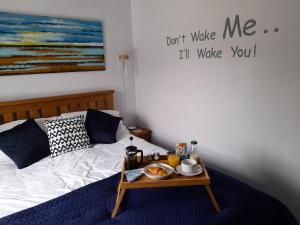 a bed with a tray of food on a table at 1 Tan Y Gerddi in Machynlleth