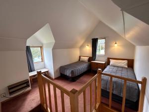 a attic room with two beds and a staircase at Masterton Motor Lodge in Masterton