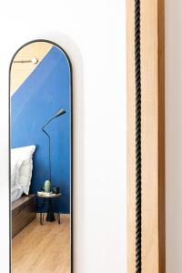 a mirror in a room with a bed and a lamp at MÔSS - Monastiraki Square Suite in Athens