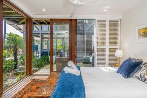 a bedroom with a bed and a large window at Above The Pass in Byron Bay