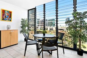uma sala de jantar com mesa e cadeiras e janelas grandes em The Patio Place near Crown Casino with Parking em Melbourne