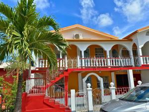 ein rotes und weißes Haus mit einer Palme in der Unterkunft The Limes Apartments in Grand Anse