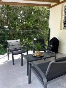 a patio with two chairs and a table with a plant on it at Villa Varte in Baie-Mahault