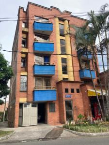 an apartment building with blue balconies and a palm tree at Full Apartamento en Medellin Itagui Centro de la moda Mayorista Poblado in Itagüí