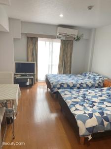 ein Hotelzimmer mit 2 Betten und einem TV in der Unterkunft Takemura Building 3F in Tokio