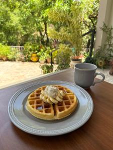 a plate of waffles with butter and a cup of coffee at Helechos Hotel in Comayagua