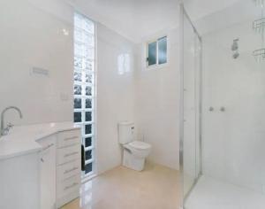 a white bathroom with a toilet and a shower at R&R Blue Diamond Luxury Studio Maryborough, Vic in Maryborough