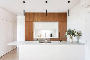 a white kitchen with a sink and wooden cabinets at 'Executive Luxury Retreat' Eco Passive Living in Sydney
