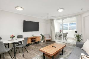 un soggiorno con tavolo e TV a parete di 'The Sand Dollar' Central Cairns Chic with Adjacent Studio a Cairns