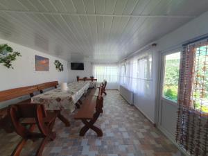 a dining room with a table and chairs and windows at Casa cu flori in Tuzla