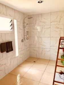 een badkamer met een douche en witte marmeren muren bij Are Ara - House of Pineapple in Titikaweka
