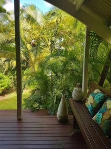 een houten veranda met een bank en palmbomen bij Are Ara - House of Pineapple in Titikaweka
