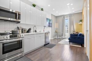 uma cozinha com armários brancos e um sofá azul em SWJ 4th and 5th - Save on 2Day+ Stays_Duplex em Nova York