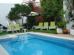 uma piscina com cadeiras verdes e brancas ao lado em Casa Claudia - Pool and Wifi em Silves