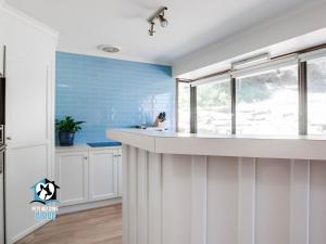 eine Küche mit einem weißen Waschbecken und einer blauen Wand in der Unterkunft In The Sand Dunes & Renovated House in Goolwa South