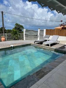 una piscina con due sedie e un tavolo di Les Appart villa Sunbay Caraibes avec piscine privative vue mer et montagne a Le François