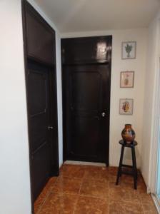 a hallway with two black doors and a stool at Casa del primo in Ixtapaluca