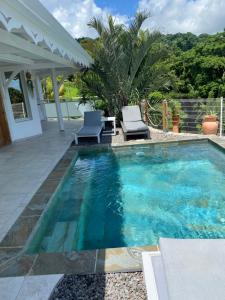 una piscina con due sedie e un tavolo di Les Appart villa Sunbay Caraibes avec piscine privative vue mer et montagne a Le François