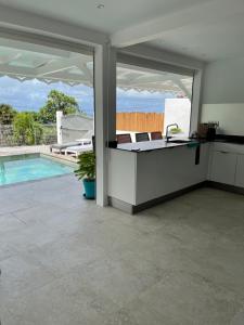 a kitchen and living room with a view of a pool at Les Appart villa Sunbay Caraibes avec piscine privative vue mer et montagne in Le François