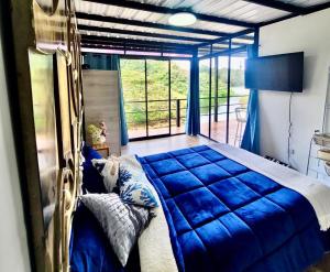1 dormitorio con cama azul y ventana grande en Cabaña Guatapé, en Guatapé