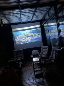 une chambre avec des chaises et un grand écran de projection dans l'établissement Cabaña Guatapé, à Guatapé