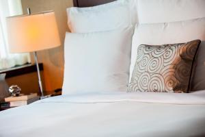 un letto bianco con cuscino e lampada di Renaissance Shanghai Zhongshan Park Hotel a Shanghai