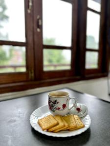 a cup of coffee and cookies on a plate at Syengden Nikunj in Darjeeling