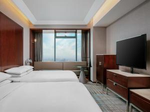 上海市にあるルネッサンス 上海 中山 公園 ホテルのベッド2台、薄型テレビが備わるホテルルームです。