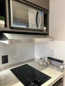 a microwave oven sitting above a stove in a kitchen at Blend Marista in Goiânia