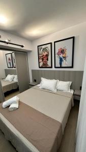 a bedroom with a large bed with four pictures on the wall at Blend Marista in Goiânia
