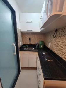 Elle comprend une petite cuisine avec des placards blancs et un évier. dans l'établissement Loft em Olaria, à Rio de Janeiro