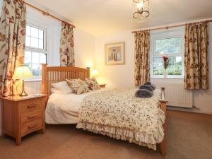 sypialnia z łóżkiem i 2 oknami w obiekcie Coombe Cottage w mieście Borrowdale Valley