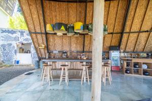 a bar with stools in a building with wooden walls at Bong Hostel Nusa Lembongan in Nusa Lembongan