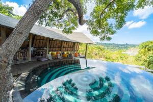 a swimming pool in front of a house with a tree at Bong Hostel Nusa Lembongan in Nusa Lembongan