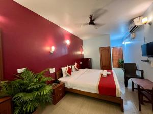 a bedroom with a bed and a red wall at Baga Beach Myron in Baga