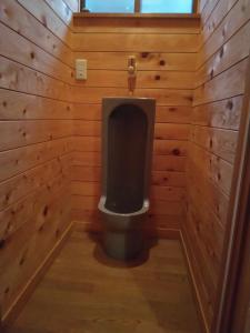 een badkamer met een toilet in een houten muur bij BANRYU 萬龍 バンリュウ in Iida